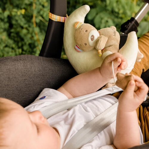 Ein Baby spiel im Kinderwagen mit der Spieluhr Teddy auf Mond.