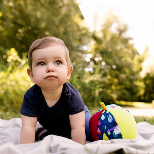 Ein Baby spielt mit dem bunten Stoffball von Fehn.