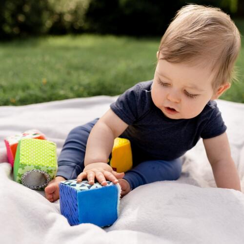 Ein Baby spielt mit den bunten Fehn Stoffwürfeln.