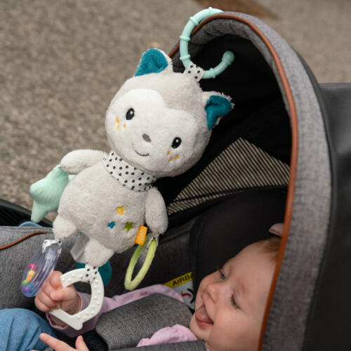 Ein Baby spielt mit der Fehn Activity Katze im Kinderwagen.