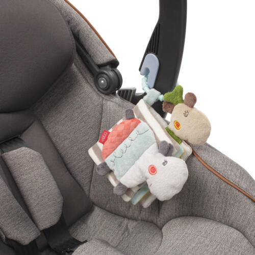 Das Stoffbuch Loopy & Lotta von Fehn ist mit dem C-Ring an einem Kindersitz befestigt.