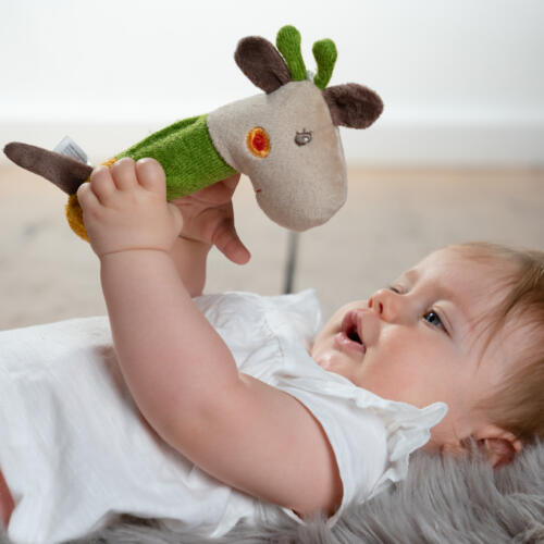 Ein Baby entdeckt die Spielfunktionen des Stabgreifers Giraffe.