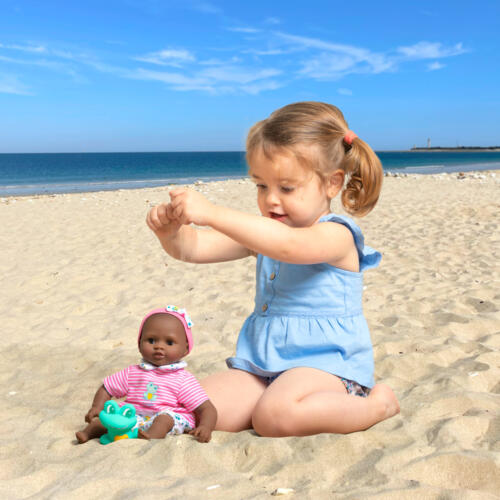 Ein Mädchen spielt mit dem Badebaby am Strand.