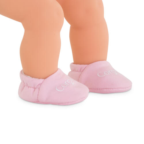 Eine Puppe trägt die rosa Puppenschuhe an den Füßen.