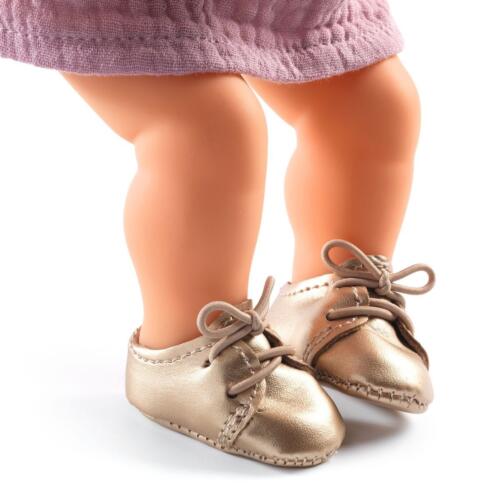 Eine Puppe trägt die goldfarbenen Puppenschuhe.
