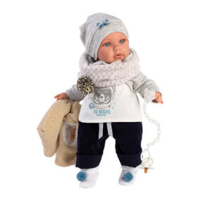 Die Babypuppe Enzo trägt wirklich coole, winterliche Puppenkleidung und hat ihren Schnuller mit Schnullerkette in der Hand.