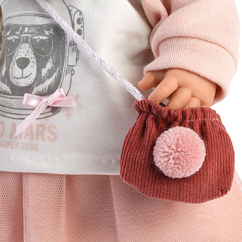 Das Detailfoto zeigt die kleine Umhängetasche aus Cord, die mit einem Bommel geschmückt ist.