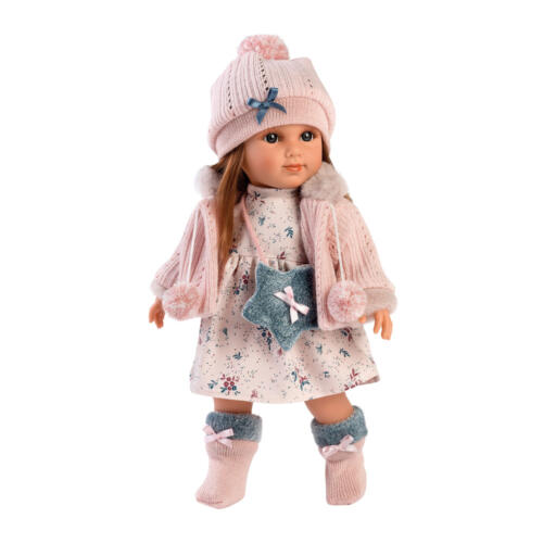 Die Puppe Nicole trägt ein hübsches, rosafarbenes Puppenoutfit mit einer niedlichen Umhängetasche.