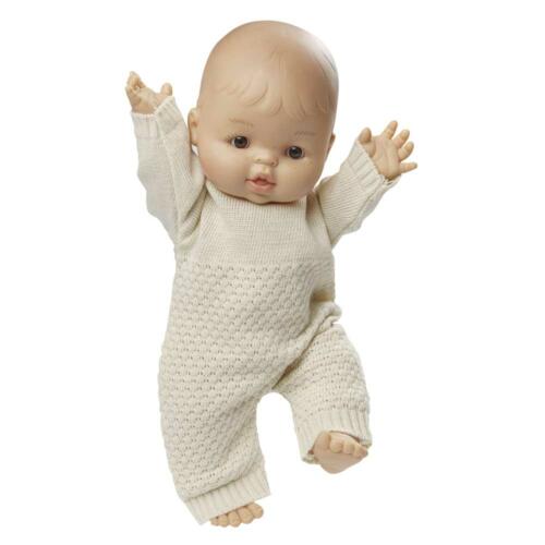 Eine Babypuppe trägt den niedlichen Strickoverall.